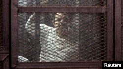 FILE - A Muslim Brotherhood supporter convicted of playing a role in the killings of 16 policemen in August 2013, stands behind bars during the trial in Cairo, Egypt, Feb. 2, 2015.