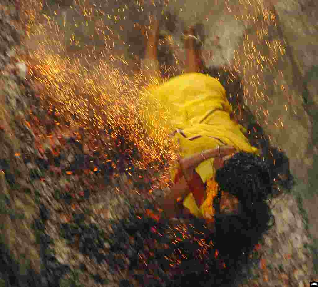 An Indian Hindu devotee falls on burning coal while holding her daughter during a coal run at the Maa Maariamma Mela in Jalandhar. The mother and daughter were both injured. 