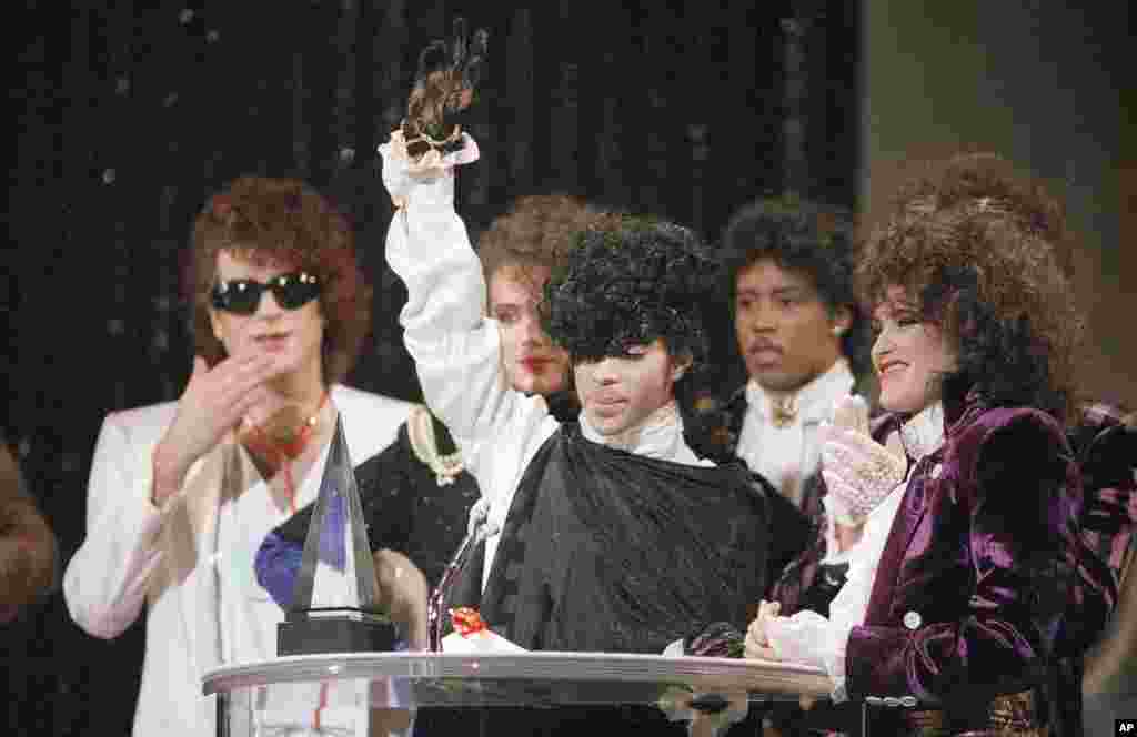 Pop vocalist Prince holds up a hand as he accepts an American Music Award for his single "When Doves Cry" during presentations at the Shrine Auditorium in Los Angeles, Jan. 28, 1985. 