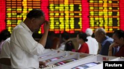 Investors look at computer screens showing stock information at a brokerage house in Shanghai, China, July 8, 2015.