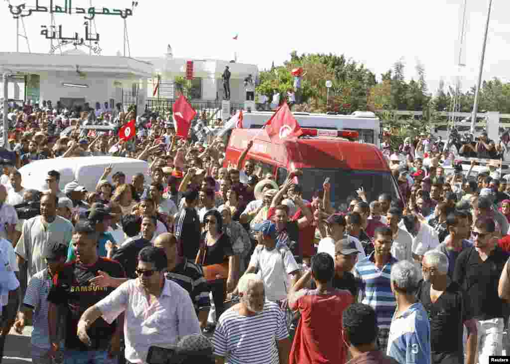 People walk beside the ambulance carrying the body of assassinated Tunisian opposition politician, Mohamed Brahmi, Tunis, July 25, 2013.&nbsp;
