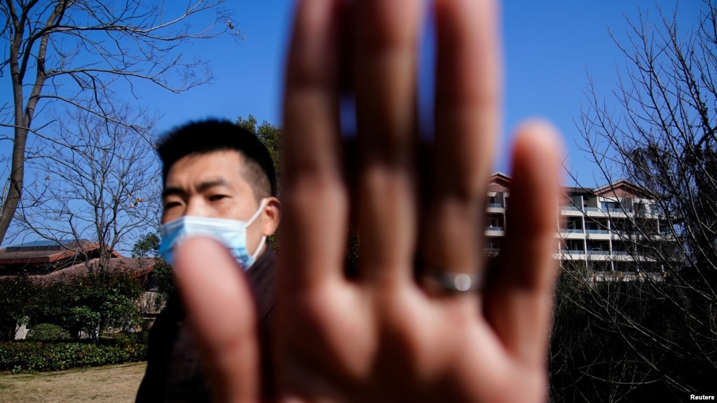 资料照片：中国安全人员阻挡新闻摄影师拍摄世界卫生组织一个专家组在武汉的行踪。（2021年2月6日）(photo:VOA)