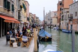 Warga Italia menikmati minuman malam aperitivo sambil duduk di bar di Venesia, Italia, setelah pemerintah setempat menghapus kebijakan karantina di tengah pandemi COVID-19, 26 April 2021.