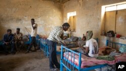 Surgeon and doctor-turned-refugee, Tewodros Tefera, checks the wounds of Abrahaley Minasbo a 22-year-old dancer and Tigrayan survivor from Mai-Kadra, Ethiopia, at the Hamdeyat Transition Center, eastern Sudan. (AP)