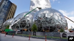 FILE - In this April 27, 2017 file photo, construction continues on three large, glass-covered domes as part of an expansion of the Amazon.com campus in downtown Seattle. Amazon said Thursday, Sept. 7, that it will spend more than $5 billion to build ano