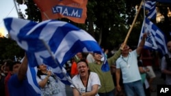 Supporters of the 'No' vote wave Greek flags after the referendum's exit poll results announced at Syntagma square, Athens, July 5, 2015.