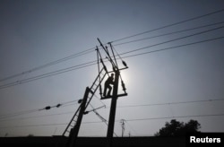 Silhouette seorang teknisi yang bekerja di jaringan listrik yang memasok listrik di pinggiran kota Lahore, Pakistan