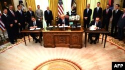 알렉산다르 부치치 세르비아 대통령(왼쪽)과 압둘라 호티 코소보 총리(오른쪽)가 4일 워싱턴 백악관에서 도널드 트럼프 미국 대통령이 지켜보는 가운데 경제 정상화 합의문에 서명했다.
