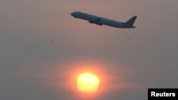 An Air India passenger plane passes the sun on a smoggy morning in Ahmedabad, India, Dec. 4, 2019.