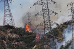 FILE - Smoke from wildfires rises from a hillside near power lines outside Azusa, Calif., June 20, 2016.