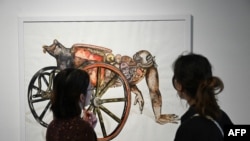 FILE - The commissioner of exposition Agnes Lacaile (L) explains the work entitled "Le temps presse" (Time is running out) at the exhibition ReThinking Collections at the AfricaMuseum in Tervuren, on January 17, 2024.