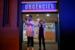 Health workers react as people applaud them from their houses, Barcelona, Spain, March 16, 2020.