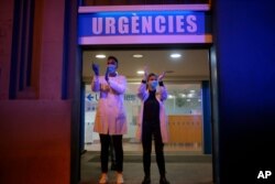 Health workers react as people applaud them from their houses, Barcelona, Spain, March 16, 2020.