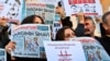 FILE - Demonstrators hold placards and copies of the Cumhuriyet daily newspaper at a protest outside an Istanbul court where about a dozen employees of the newspaper are being tried on charges of aiding terror groups, Oct. 31, 2017.
