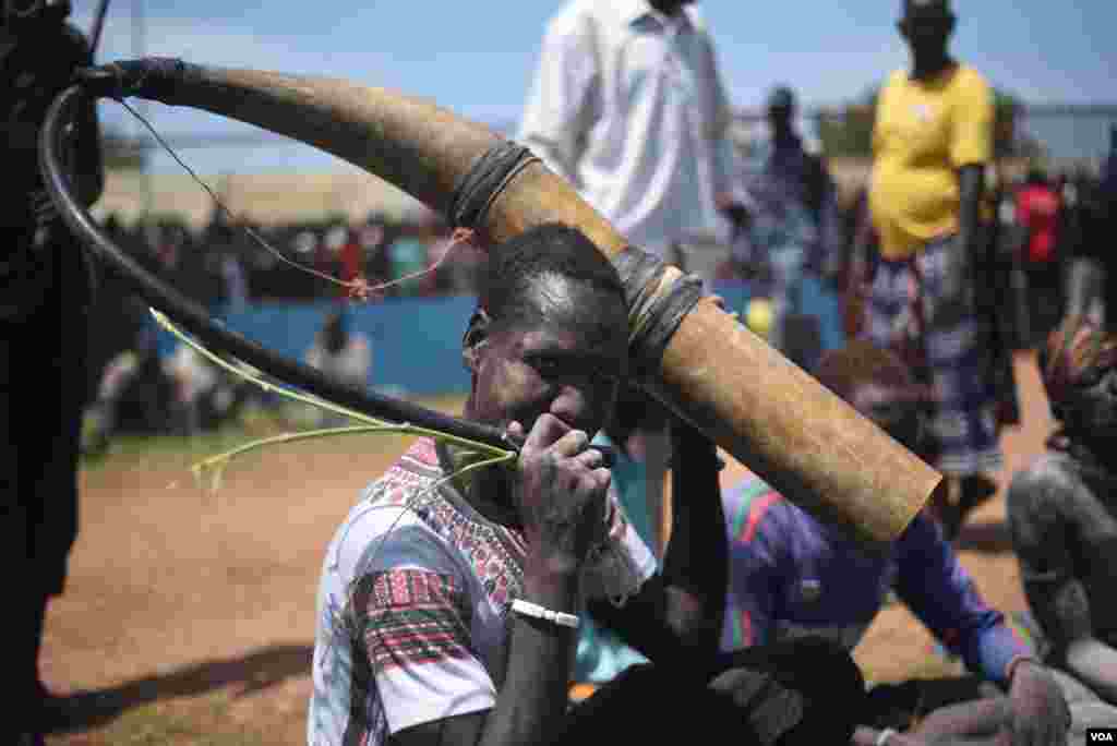 A Mundari wrestling fan blows a cow horn trumpet during the "Wrestling for Peace" tournament at Juba Stadium in South Sudan's capital, April 16, 2016. (J. Patinkin/VOA)