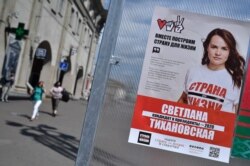 People walk past a campaign poster of opposition presidential candidate Svetlana Tikhanovskaya in Minsk, Belarus, July 30, 2020.