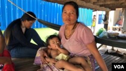 Seum Sreyoun, an unemployed garment worker, sat with her family underneath their home in Pongro village, Kampong Speu province, Cambodia, April 5, 2020. (Sun Narin/VOA Khmer)