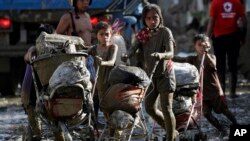 Children push baby strollers full of belongings they retrieved from their homes damaged by Typhoon Vamco in Rodriguez, Rizal province, Philippines.