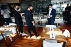 German Labour Minister Hubertus Heil (R) wears a face mask as he talks to staff during his visit at the restaurant "Funky Fish" in Berlin, Germany, May 19, 2020,