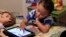 FILE - Frankie Thevenot, 3, plays with an iPad in his bedroom at his home in Metairie, La.  
