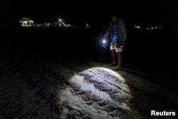 CURMA's operations director Carlos Tamayo, 44, looks at the tracks of a mother turtle who failed to lay eggs on the beach, at Bacnotan, La Union, Philippines, December 21, 2022. (REUTERS/Eloisa Lopez)