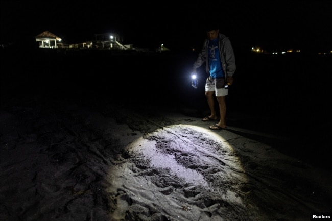 CURMA's operations director Carlos Tamayo, 44, looks at the tracks of a mother turtle who failed to lay eggs on the beach, at Bacnotan, La Union, Philippines, December 21, 2022. (REUTERS/Eloisa Lopez)