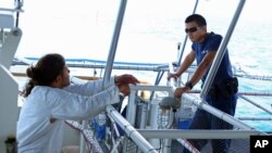 U.S. Coast Guard firemen Eddie Toledano (r) talks to a Cuban migrant on board the USCG Cutter Charles David Jr. in the Florida Straits, May 17, 2015.