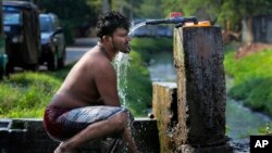  Sri Lankan man takes a bath from a roadside tap to cool himself 