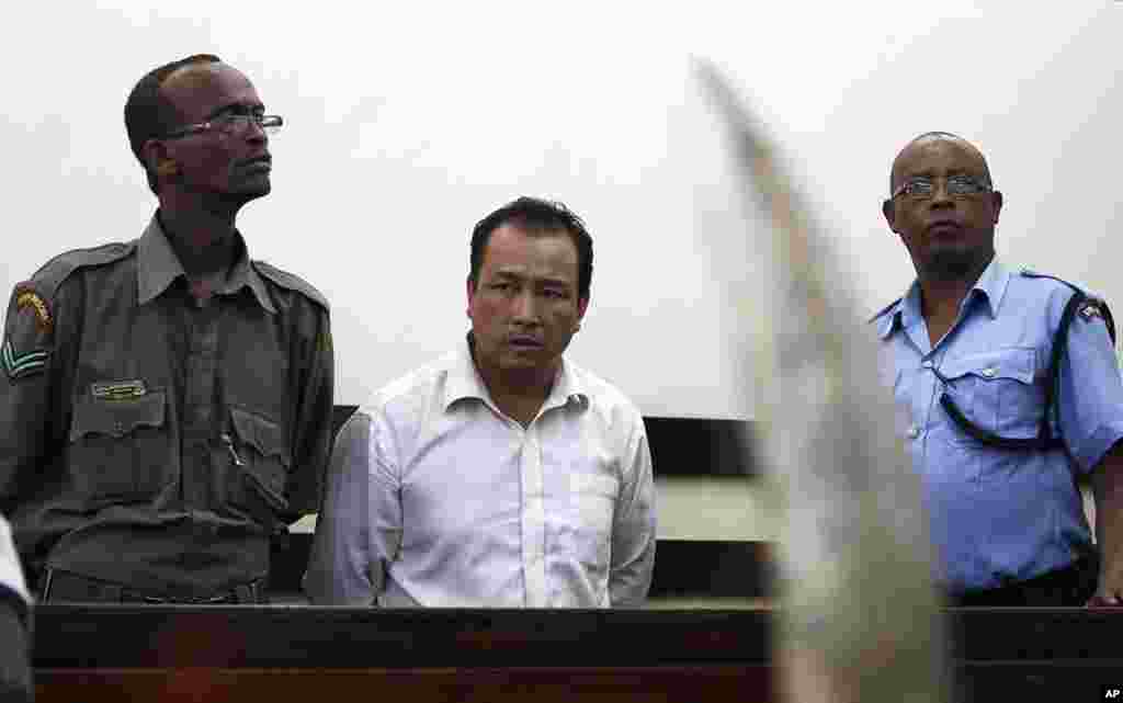 Kenya security stand guard over Tang Yong Jian, a Chinese national who pleaded guilty in the dock of the Makadara Law courts in Kenya&#39;s capital, Nairobi, January 28, 2014. Tang, 40, was arrested at the Jomo Kenyatta International airport in Nairobi trying to smuggle 3.4 kilograms of raw ivory to Giuangzhou, China. His punishment was $233,000 or seven years in prison.