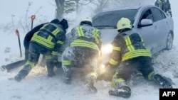 На снимке спасатели толкают автомобиль во время сильного снегопада в Одесской области, 27 ноября 2023 г..