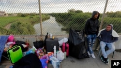FILE - In this Nov. 2, 2018, file photo, Yenly Morales, left, and Yenly Herrera, immigrants from Cuba seeking asylum in the United States, wait on the Brownsville and Matamoros International Bridge in Matamoros, Mexico.