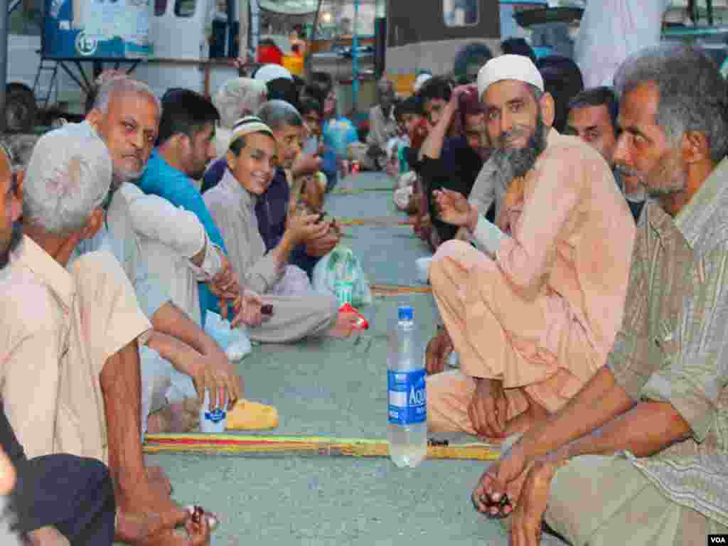 سڑک پر روزہ کھولنے والے افراد دعاوٴں میں مصروف ہیں