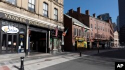 A block of closed restaurants on a deserted street ends at Faneuil Hall, right, April 4, 2020, in Boston. The area is usually busy with tourists, but tourism is nearly nonexistent during the coronavirus outbreak.