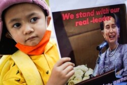 A child holds a picture of leader Aung San Suu Kyi in Bangkok, Feb. 3, 2021.