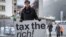 Austrian Marlene Engelhorn, whose family owns Germany's chemical giant BASF, poses with a placard reading "Tax the rich!" at the entrance of the Congress center on the opening of the annual meeting of the World Economic Forum in Davos, on Jan. 15, 2024. 