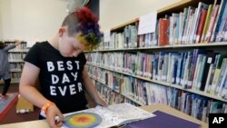 Sam yang berusia 9 tahun sedang membaca buku di perpustakaan Bay Area Rainbow Day Camp di El Cerrito, California, 12 Juli 2017.