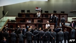 Protes anggota parlemen pro-demokrasi (atas) diblokir oleh keamanan (bawah) saat berlangsungnya debat tentang undang-undang yang melarang penghinaan lagu kebangsaan China, selama sesi Dewan Legislatif (Legco) di Hong Kong, 4 Juni 2020. 