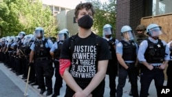 A demonstrator stands in front of Chicago Police officers during the March for Justice in honor of George Floyd Saturday, June 6, 2020, in Chicago. Demonstrators who gathered at Union Park marched through the city's West Side on Saturday afternoon,…