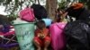 Un niño emplea un teléfono celular entre sus pertenencias después de que él y su familia cruzaron en bote el río Arauca, la frontera natural entre Venezuela y Colombia, hacia Arauquita, Colombia, el viernes 26 de marzo de 2021.