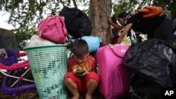Un niño emplea un teléfono celular entre sus pertenencias después de que él y su familia cruzaron en bote el río Arauca, la frontera natural entre Venezuela y Colombia, hacia Arauquita, Colombia, el viernes 26 de marzo de 2021.