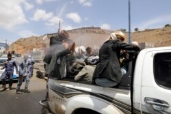 FILE - A health worker sprays disinfectant on people riding on the back of a pick-up truck while the spread of the coronavirus disease (COVID-19) continues, on the outskirts of Sanaa, Yemen, April 13, 2020.