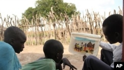 Isaiah Deng Mayom, right, Carter Center field officer, uses a flip chart to show children how to avoid contracting guinea worm, Lakes State, Sudan, Nov. 4, 2010.