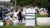 Seorang warga bernama Lori Butler tampak menyeka keningnya saat ia berusaha memindahkan puing puing dari rumahnya yang terendam banjir akibat diterjang badai Ida di LaPlace, Louisiana, AS, pada 7 September 2021. (Foto: AP)