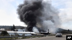 Smoke rises from a factory hit during clashes by Syrian security forces and gunmen loyal to ousted President Bashar al-Assad, on the outskirts of Latakia, Syria, March 7, 2025. 