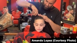 Austin Lopez reads a book to Amir Shalash as he gets his hair cut at Prince Cuts, Lexington, KY