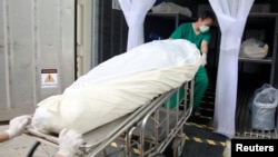 Health care workers move a dead body to a refrigerated container after a hospital morgue overwhelmed by COVID-19 deaths as the country struggles to deal with its biggest outbreak to date, in Pathum Thani, Thailand, July 31, 2021.