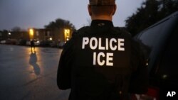 FILE - U.S. Immigration and Customs Enforcement (ICE) agents look for an undocumented immigrant during an early morning raid in Dallas, March 6, 2015. On Friday, agents raided a Tennessee meat processing plant and arrested 97 people.
