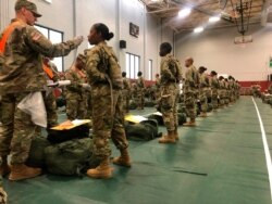 FILE - In this image provided by the U.S. Army, recent Army basic combat training graduates have their temperatures, taken as a precaution during the coronavirus pandemic, as they arrive at Fort Lee, Va., March 31, 2020.