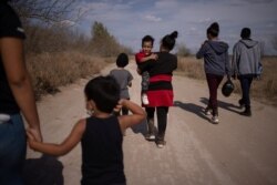 Jefferson, un niño de 3 años de El Salvador, camina de la mano con su madre Irma, através de un camino de tierra después de cruzar el río Grande hacia Estados Unidos desde México en Penitas, Texas, EE. UU., el 5 de marzo de 2021.