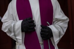A priest wearing a gloves to protect against coronavirus waits in front the cemetery chapel during the coronavirus outbreak in Madrid, Spain, March 27, 2020.